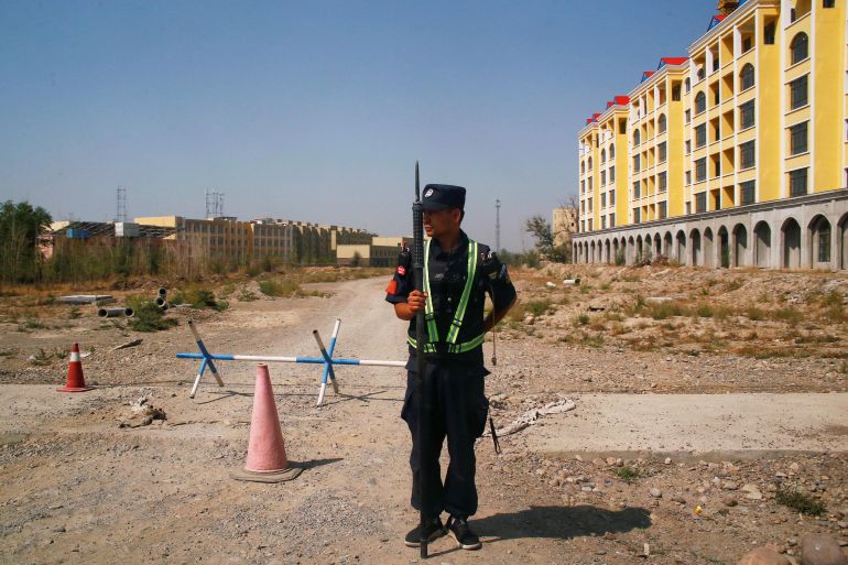 Um policial chinês se posiciona à beira da estrada perto do que é oficialmente chamado de centro de educação profissional em Yining, na Região Autônoma Uigur de Xinjiang, China