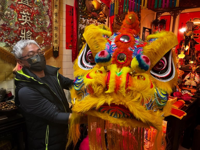 Wang Qing-zhong, who heads the Ching Ho Kuang Lion Dance Troupe in Taipei displays one of his troupe’s lion masks. It has fluffy yellow eye lashes, red and black eyes rimmed in white and a yellow fringe moustache