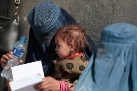 A displaced Afghan woman holds her child