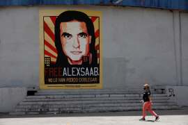 A woman walks by a mural in support of the liberation of Colombian businessman and envoy Alex Saab in Caracas, Venezuela