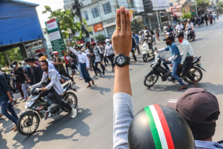A man riding a motorcycle pylon greets with other fingers three other motorcycle protesters in Mandalay during protests in April 2021. 