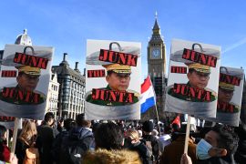 Protesters supporting Myanmar's anti-coup movement standing in front of Big Ben on a sunny day in London hold placards reading 'Junk the Junta'