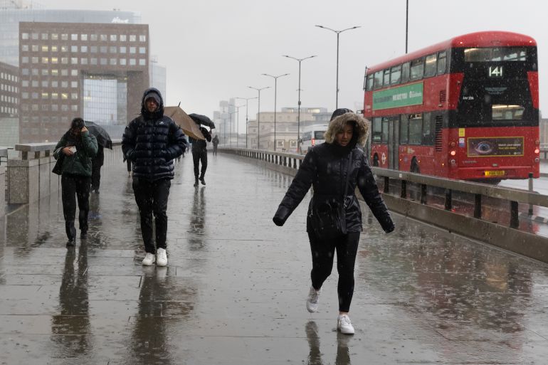 People walk across London Bridge during wet and windy weather