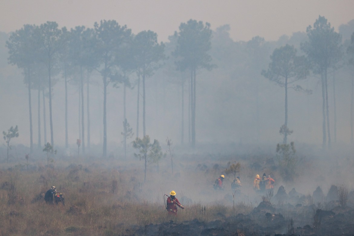 Firefighters work to put out a wildfire in the town of Santo Tome
