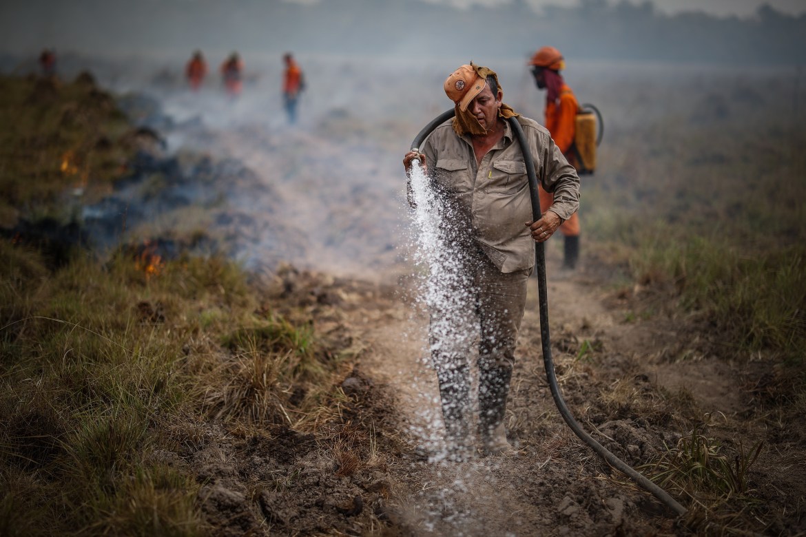 Firefighters work to put out a wildfire in the town of Santo Tome