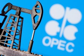A 3D printed oil pump jack is seen in front of displayed OPEC logo