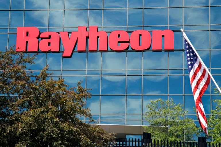 An American flag flies in front of the facade of Raytheon's Integrated Defense Systems facility