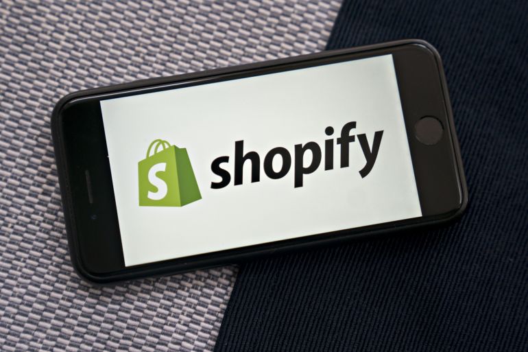 The Shopify Inc. logo is displayed on a smartphone