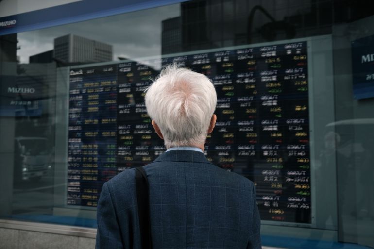 A man looks at an electronic stock board