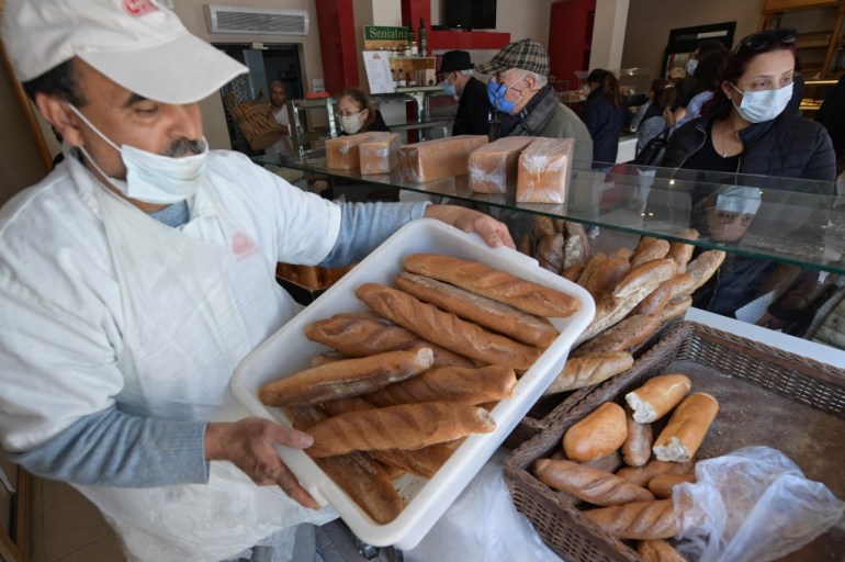 A worker carries fresh loaves of bread at a bakery in the El Menzah area of Tunis 