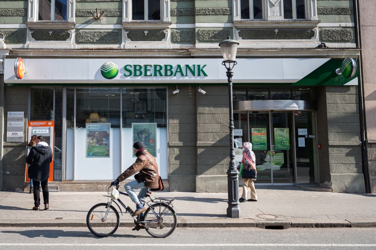 A man cycles past one of the Slovenian branches of the Russian state-owned bank Sberbank, in Ljubljana