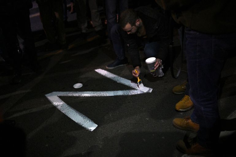 A protester paints the "Z" sign on a street, in reference to Russian tanks marked with the letter, during a rally organised by Serbian right-wing organisations in support of Russian invasion in Ukraine, in Belgrade March 4, 2022. - Around a thousand Serbian ultra nationalist supporters marched in Belgrade in support of the Russian invasion of Ukraine.
