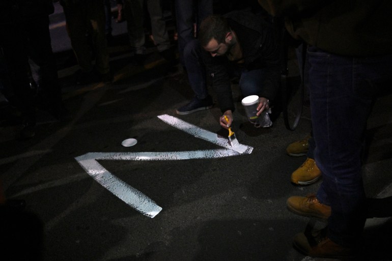 A protester paints the "Z" sign on a street, in reference to Russian tanks marked with the letter, during a rally organized by Serbian right-wing organisations in support of Russian invasion in Ukraine, in Belgrade March 4, 2022. - Around a thousand Serbian ultra nationalist supporters marched in Belgrade in support of the Russian invasion of Ukraine.