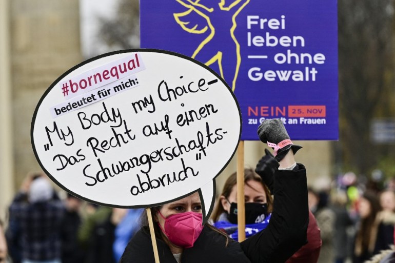 a protester holds up a sign reading "My Body my choice- the right to abortion" during a demonstration against violence against women called by women's right organisation "Terre des Femmes" in front of the Brandenburg Gate in Berlin