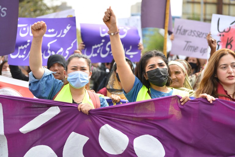 Aurat March protesters hold placards.