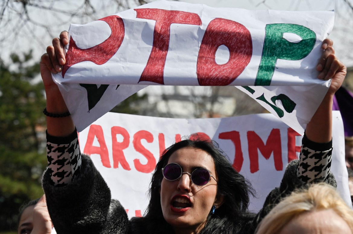 A woman shouts slogans and holds up a sign during a rally for gender equality and against violence towards women to mark the International Women's Day in Pristina