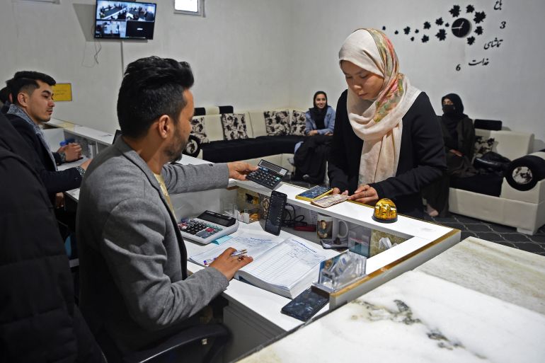 A university student exchanges cryptocurrency for cash at a currency exchange office in Herat