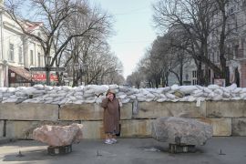 A resident stands next to a sandbag barricade in Odesa