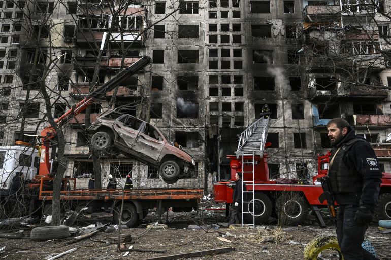 A crane removes a ruined car from in front of a destroyed apartment building after it was shelled in the northwestern Obolon district of Kyiv