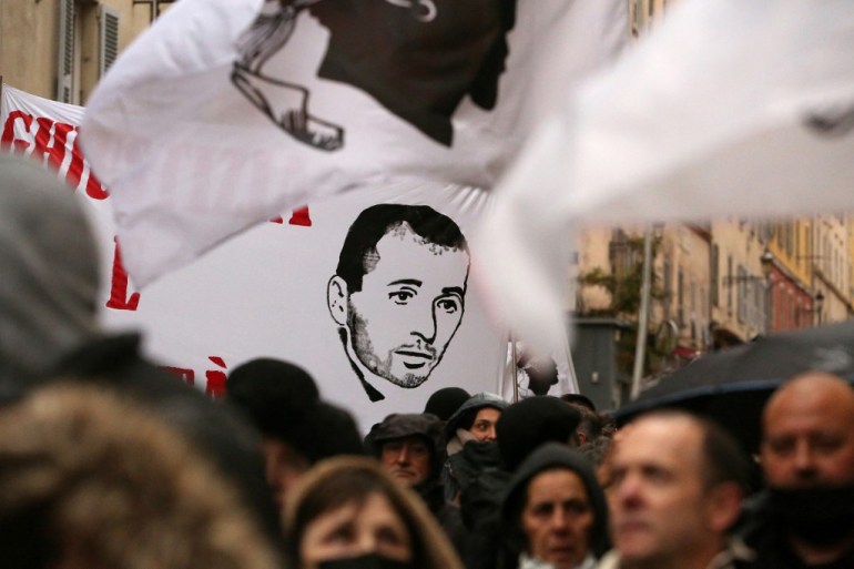 Protesters hold a banner depicting Yvan Colonna in Bastia, Corsica