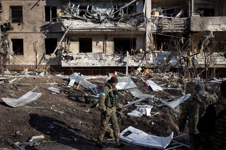 A Ukraine soldier inspects the rubble of a destroyed apartment building in Kyiv on March 15, 2022, after strikes on residential areas killed at least two people, Ukraine emergency services said as Russian troops intensified their attacks on the Ukrainian capital. - A series of powerful explosions rocked residential districts of Kyiv early today killing two people, just hours before talks between Ukraine and Russia were set to resume. (Photo by FADEL SENNA / AFP)