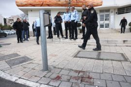 Israeli security forces stand near a blood-stained pavement in Jerusalem