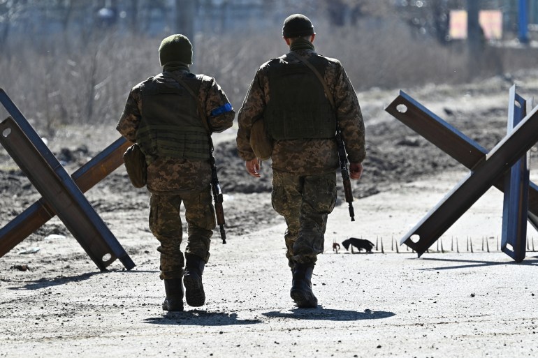 Ukrainian soldiers walk on the front line, near Kyiv on March 20, 2022.