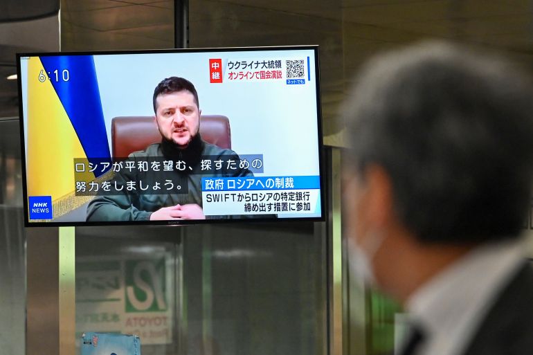 Pedestrian looks at broadcast of Ukrainian President Volodymyr Zelenskyy delivering a virtual address to Japan's parliament in Tokyo
