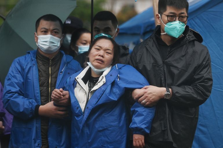 A grieving woman is held up by two men as she visits the site of the China Eastern crash