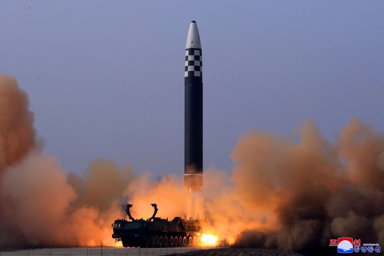 The Hwasong-17 - black with a white nose cone - launches into the sky amid smoke and orange flame