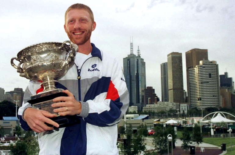 Germany's Boris Becker smiles while holding his trophy with the Melbourne city skyline
