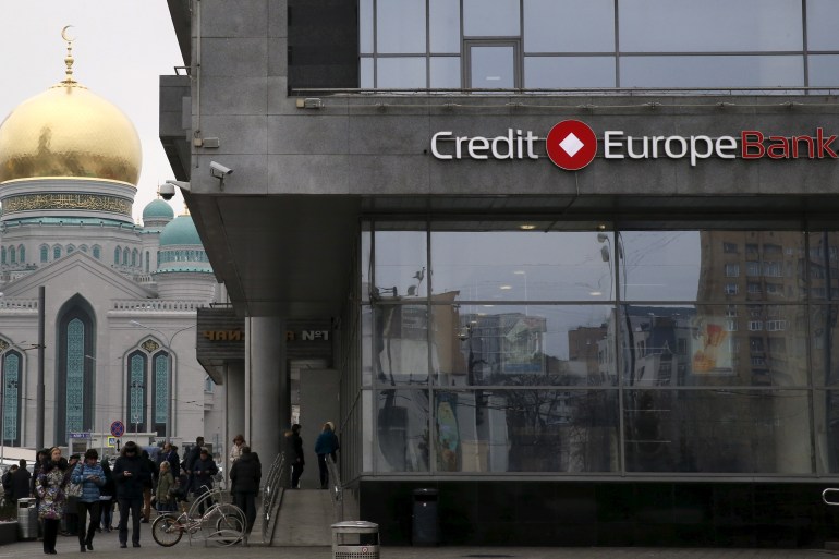 People walk near a branch of the Credit Europe Bank in Moscow.