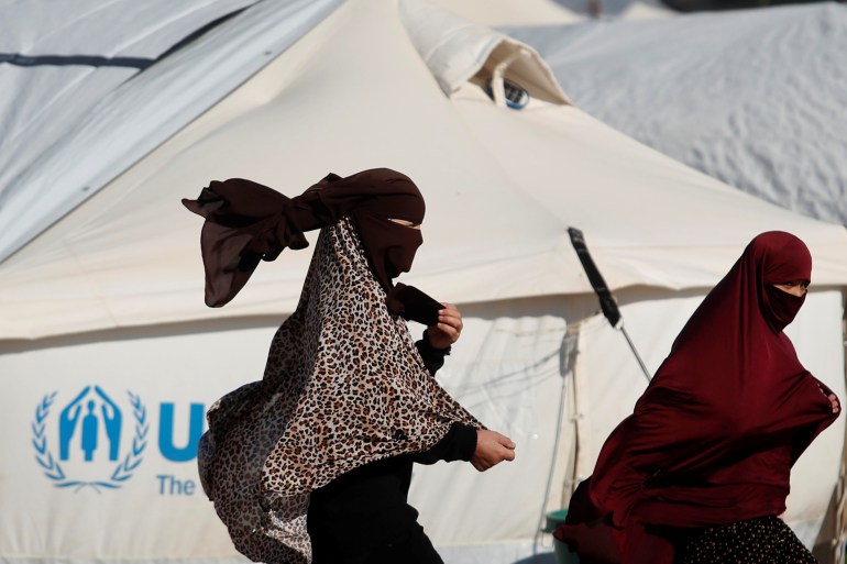 Women walk past a tent in al-Hol camp, Syria, January 8, 2020