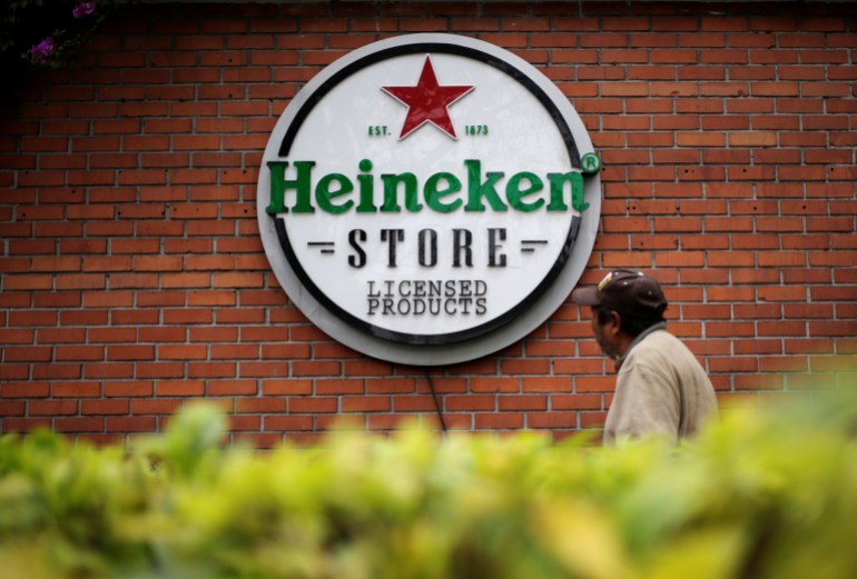A man walks past a logo at the Cuauhtemoc Moctezuma brewery, a subsidiary of Heineken, 