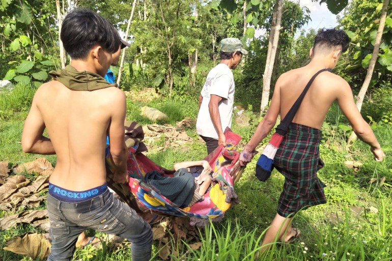 Three villagers carry a sick person on an improvised stretcher into the forest after they were forced to flee in Myanmar's Kayah state