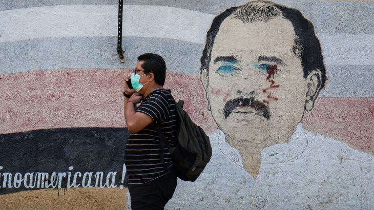 A man walks by a mural of Daniel Ortega