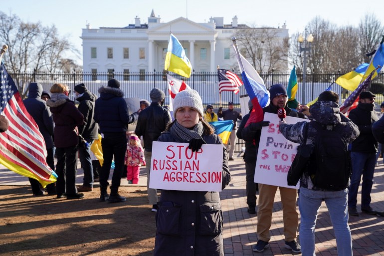 A woman holds a sign that reads 'Stop Russia Aggression' outside the White House