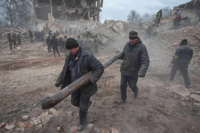 People remove debris at the site of a military base building