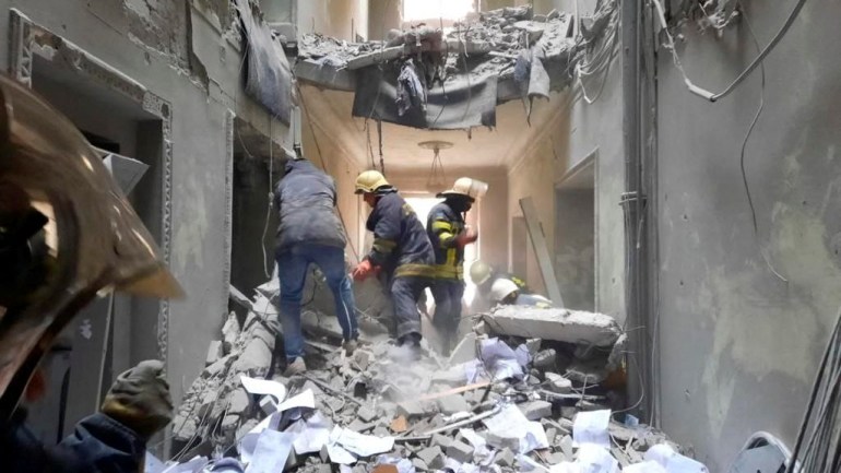 Rescuers are seen in a building, which city officials said was damaged by a missile, in central Kharkiv,