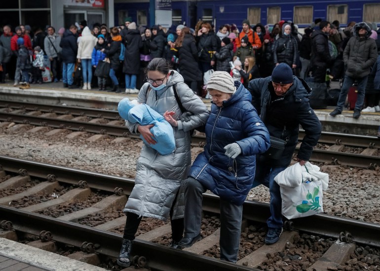 People walk through railroad tracks to board an evacuation train from Kyiv to Lviv at Kyiv central train station