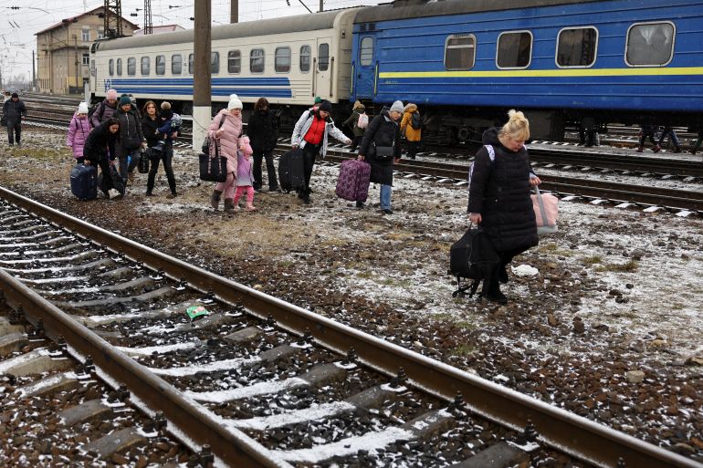 People walk with their luggage along railway tracks in Lviv, Ukraine