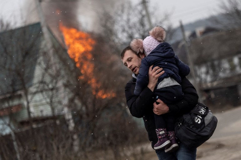 A man and a child are seen escaping from the town of Irpin