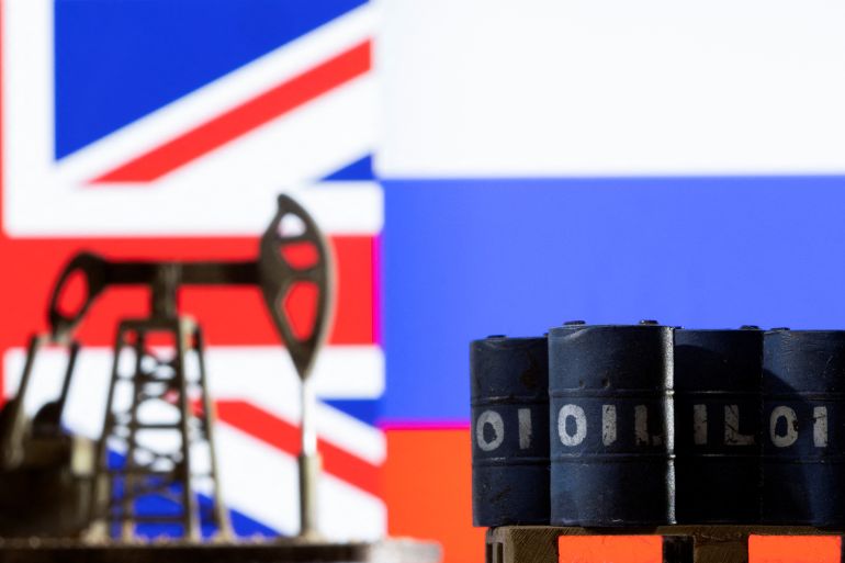 Models of pump jack and oil barrels are seen in front of the displayed UK and Russia flag colour