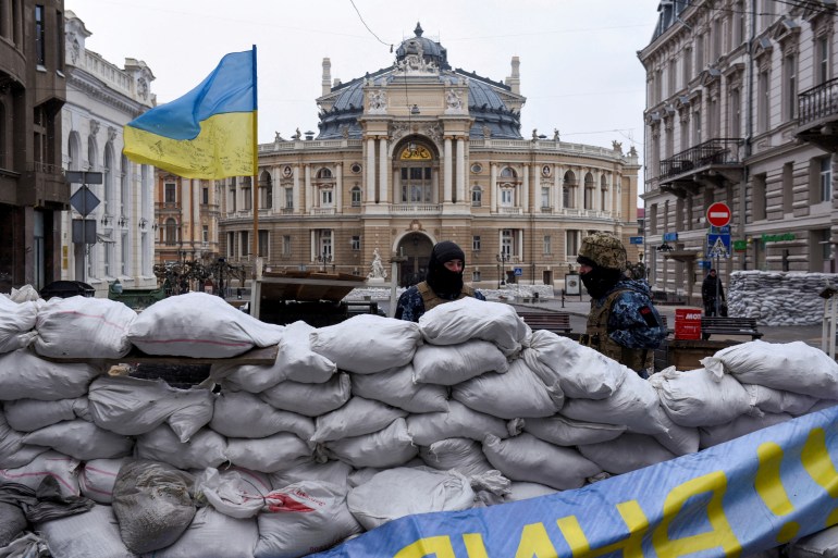 Ukrainian soldiers are seen standing guard behind a barricade in Odesa