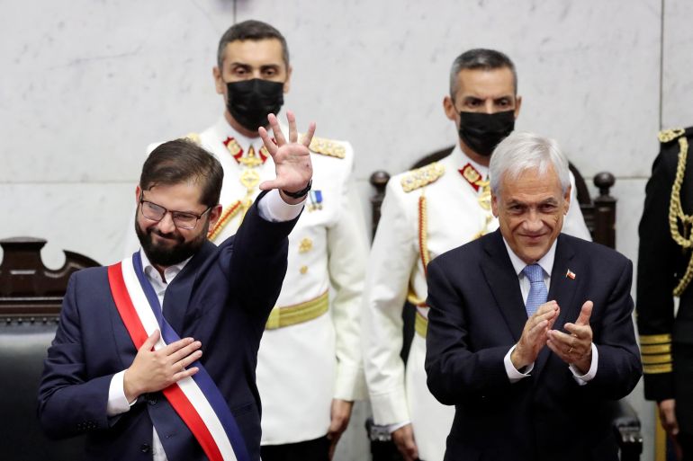 Gabriel Boric waves as former President Sebastian Pinera stands next to him