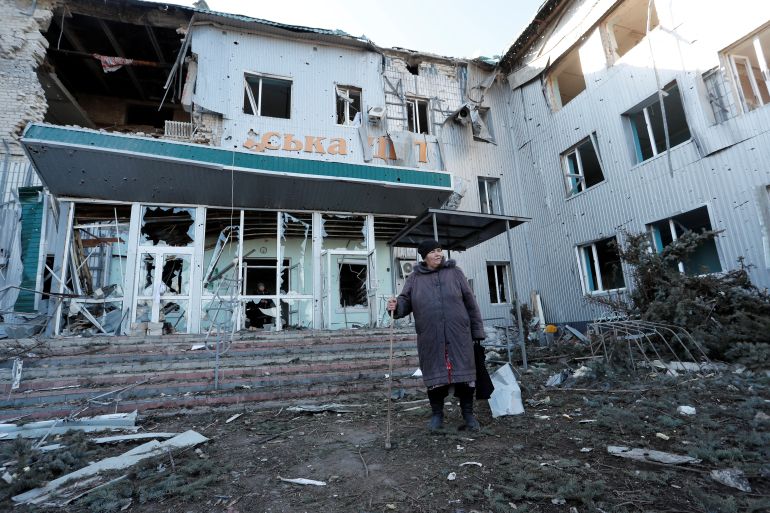 A woman stands outside a local hospital, which was destroyed during Ukraine-Russia conflict