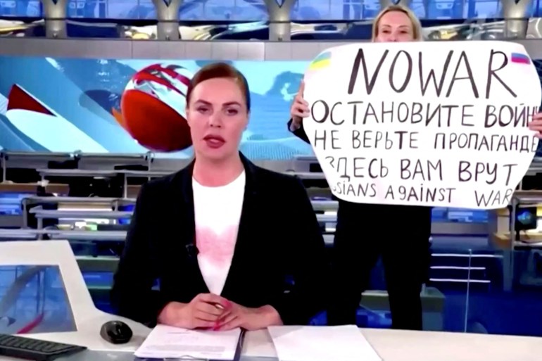 A person interrupts a live news bulletin on Russia's state TV "Channel One" holding up a sign that reads "NO WAR
