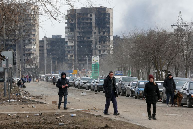 A view shows people and a line of cars near blocks of flats destroyed during Ukraine-Russia conflict, as evacuees leave the besieged southern port city of Mariupol,