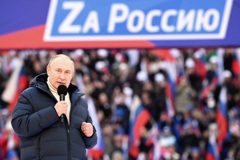 Russian President Vladimir Putin delivers a speech during a concert marking the eighth anniversary of Russia's annexation of Crimea at Luzhniki Stadium in Moscow.  The banner reads: "For Russia". 