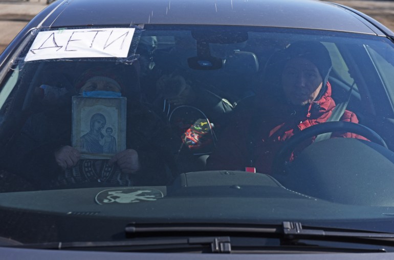 Local residents sit in a car as they leave the besieged southern port city of Mariupol 